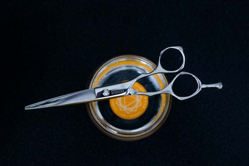 Professional beard scissors resting on a neatly trimmed beard with grooming tools in soft natural light